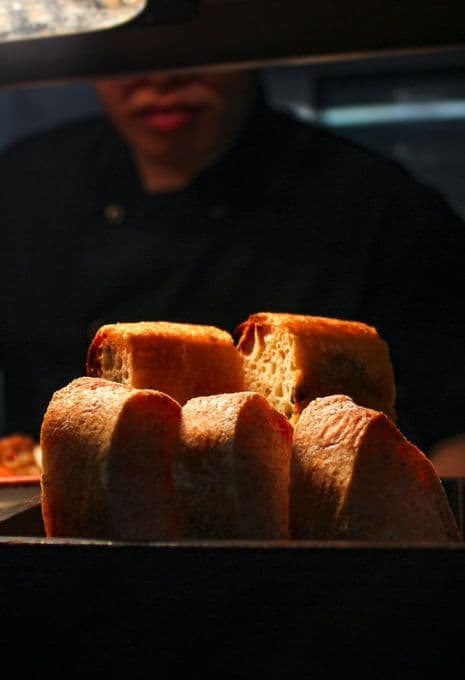 A cook passing focaccia at the kitchen line